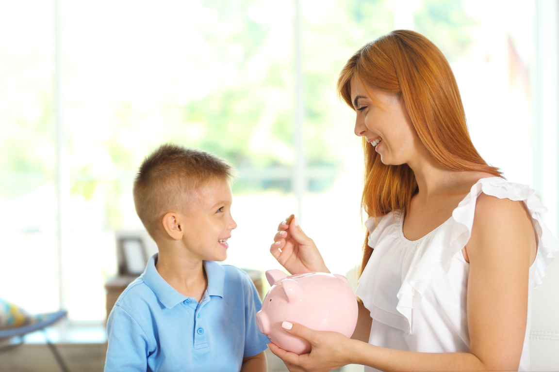 Mother and Little Boy Putting Coins into Piggy Bank